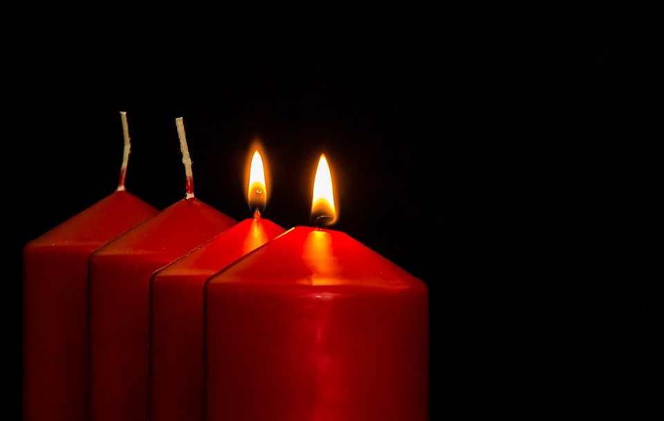 Neljä punaista kynttilää rinnakkain, joista kaksi palaa.