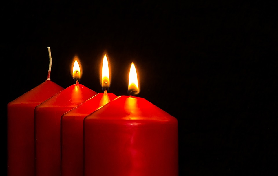 Neljä punaista kynttilää rinnakkain, joista kolme palaa.