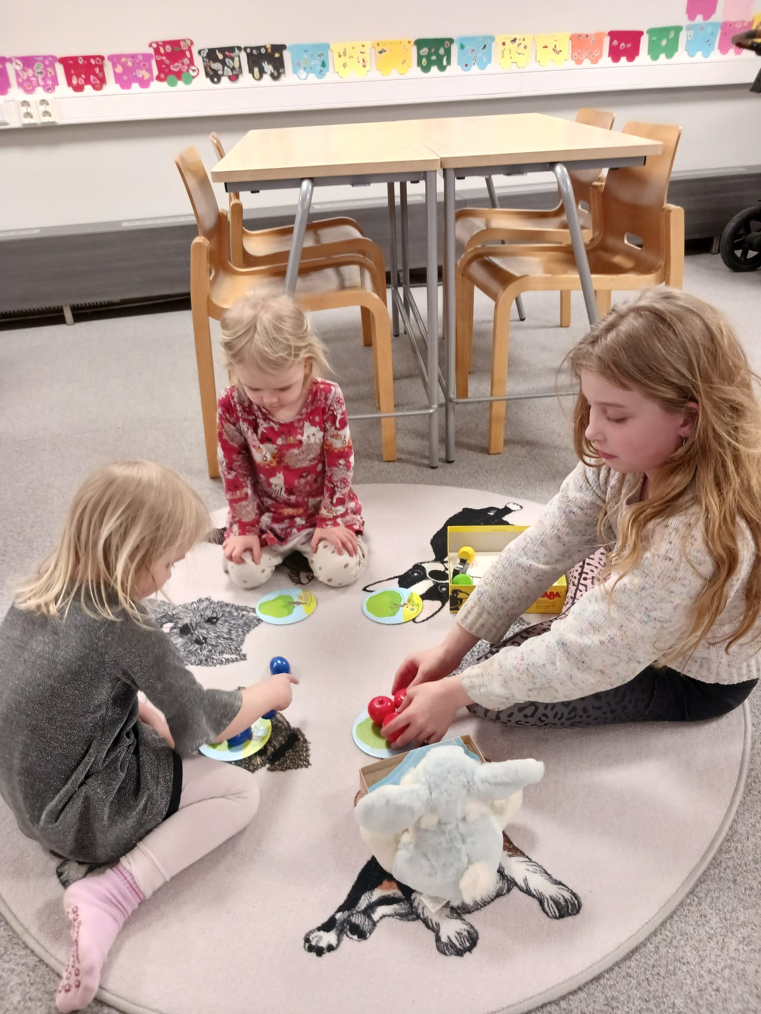 Kolme lasta pelaa lattialla.