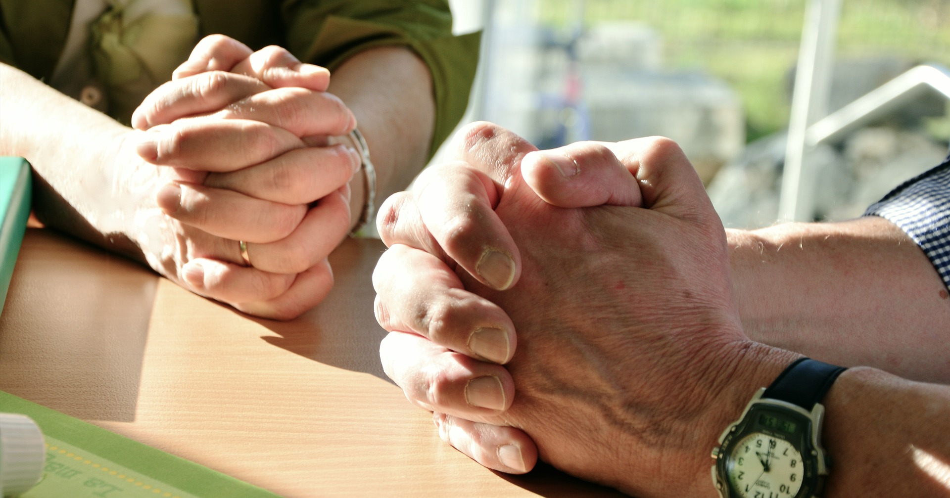 Kahden henkilön rukoukseen ristit kädet.